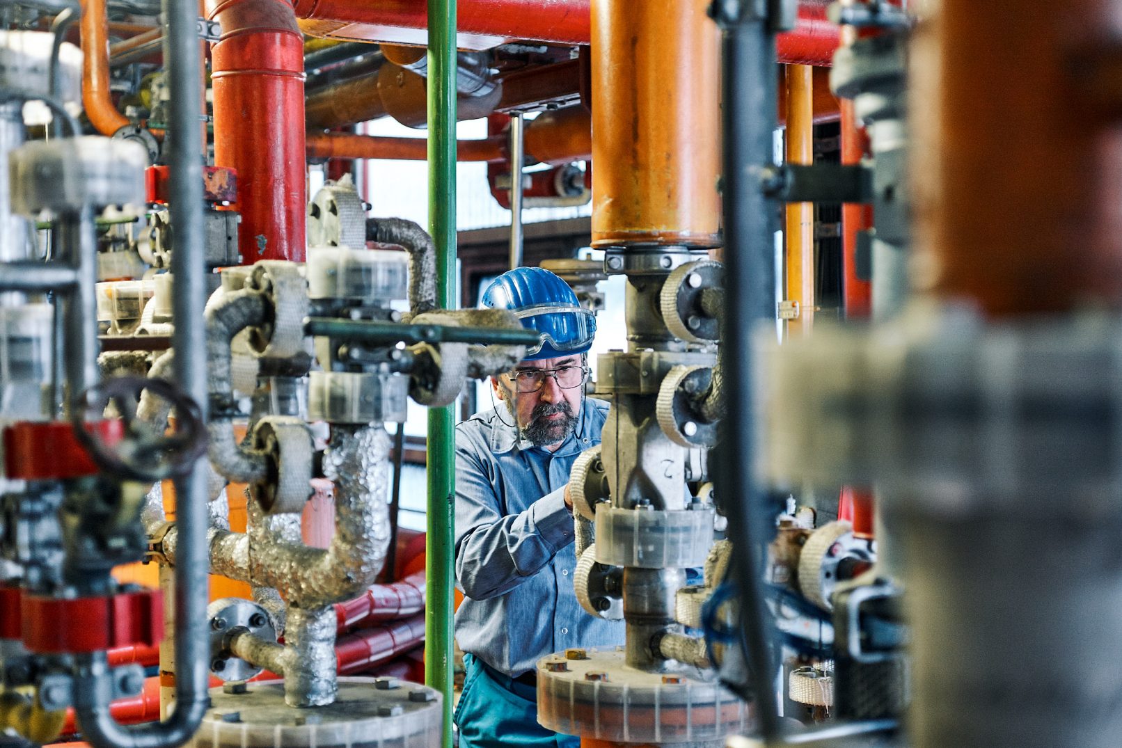 Mitarbeiter der chemischen Industrie in Gewirr von Röhren und Leitungen